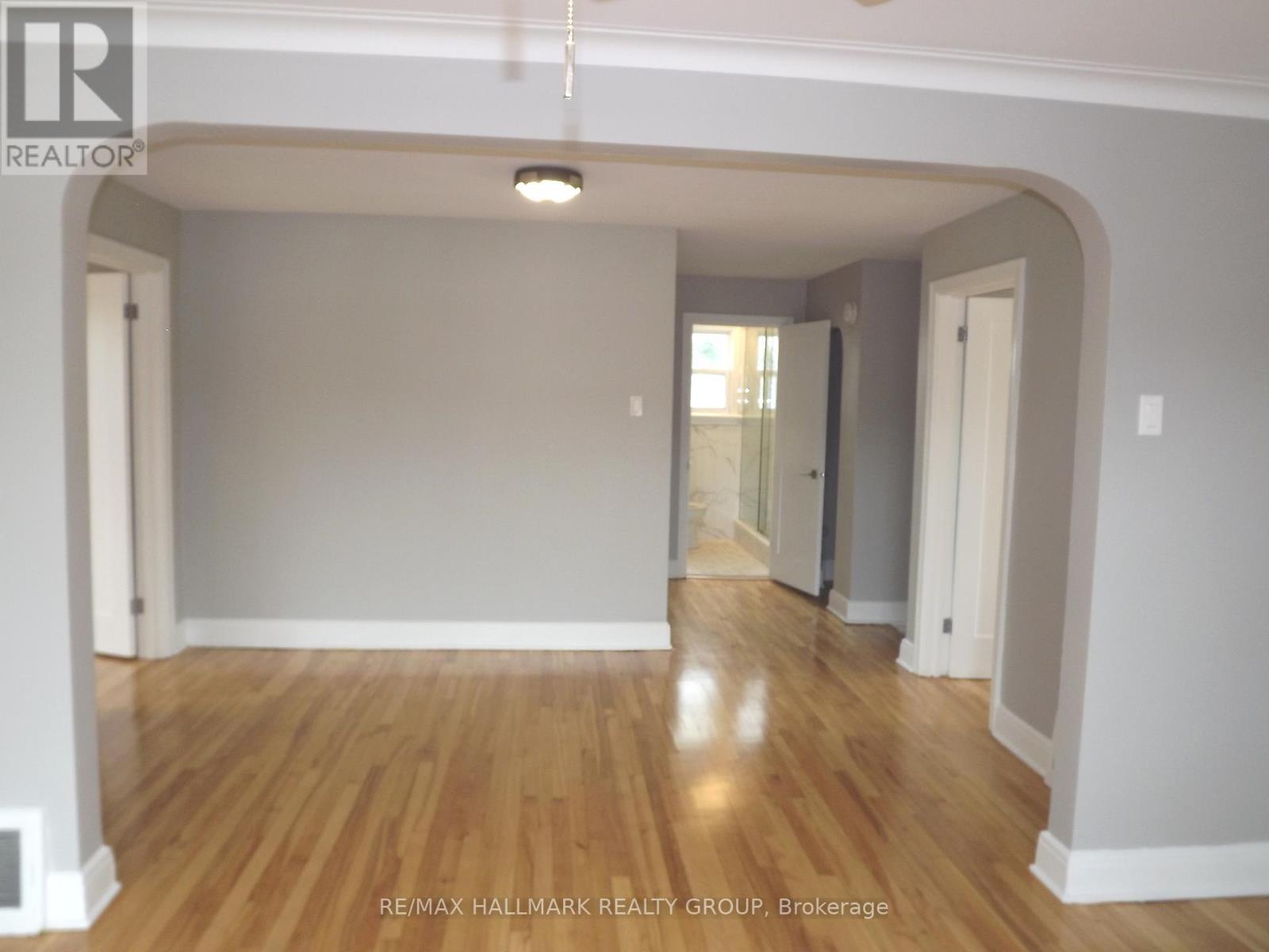 A spacious room with wooden flooring and white walls.