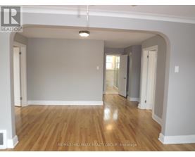 A spacious room with wooden flooring and white walls.