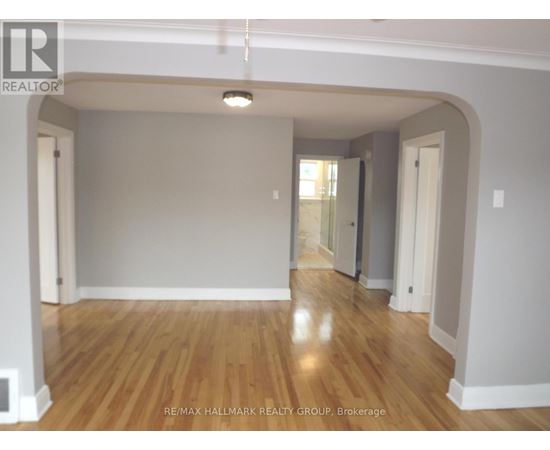 A spacious room with wooden flooring and white walls.