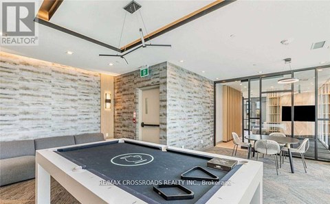 A modern living room with a pool table and a stone wall.