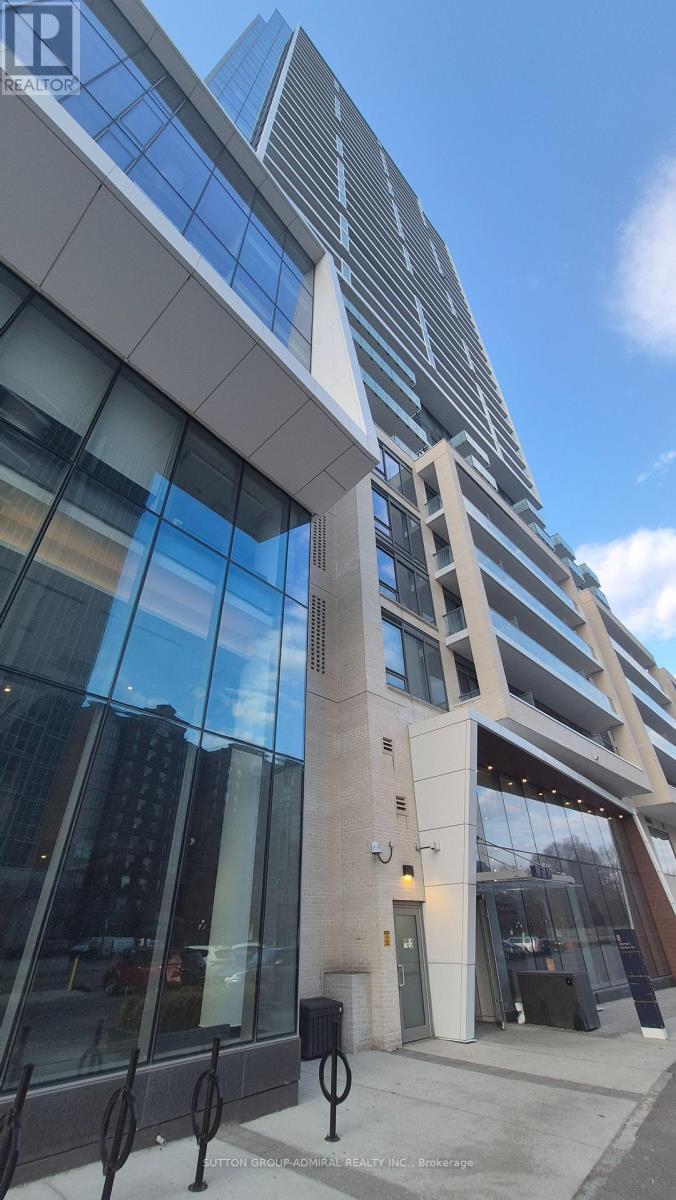 A modern building with a glass facade and a tall tower in the background.
