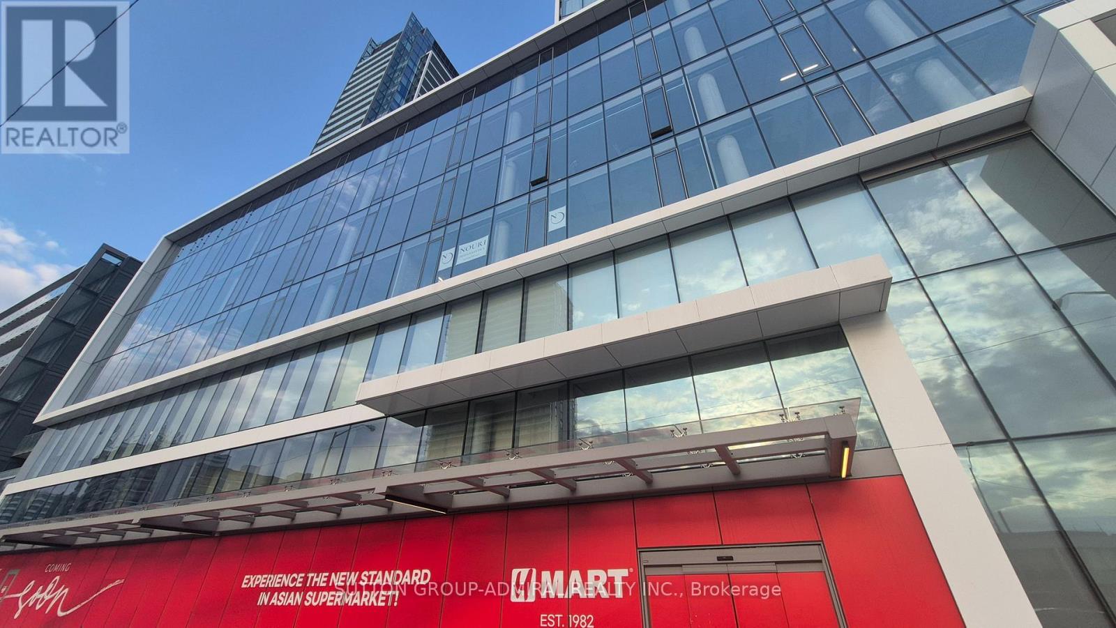 A tall building with a red sign that says "Elevate the new standard. WASAN SUPERMARKET!".
