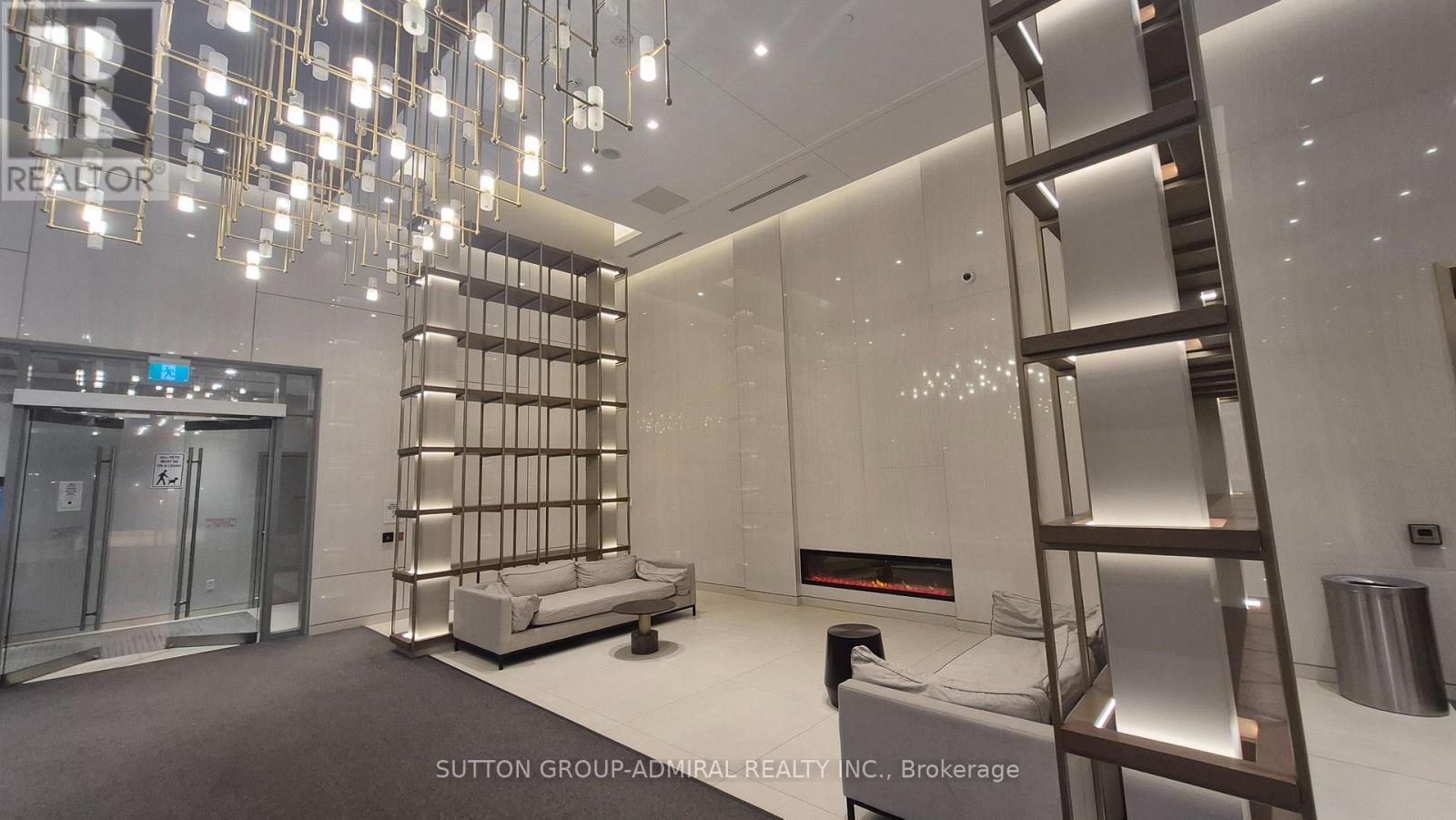 A modern, well-lit room with a glass elevator and a metal staircase.