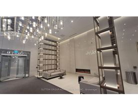 A modern, well-lit room with a glass elevator and a metal staircase.