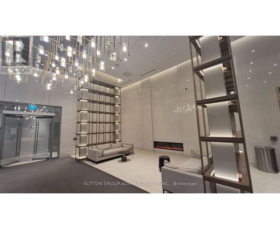 A modern, well-lit room with a glass elevator and a metal staircase.