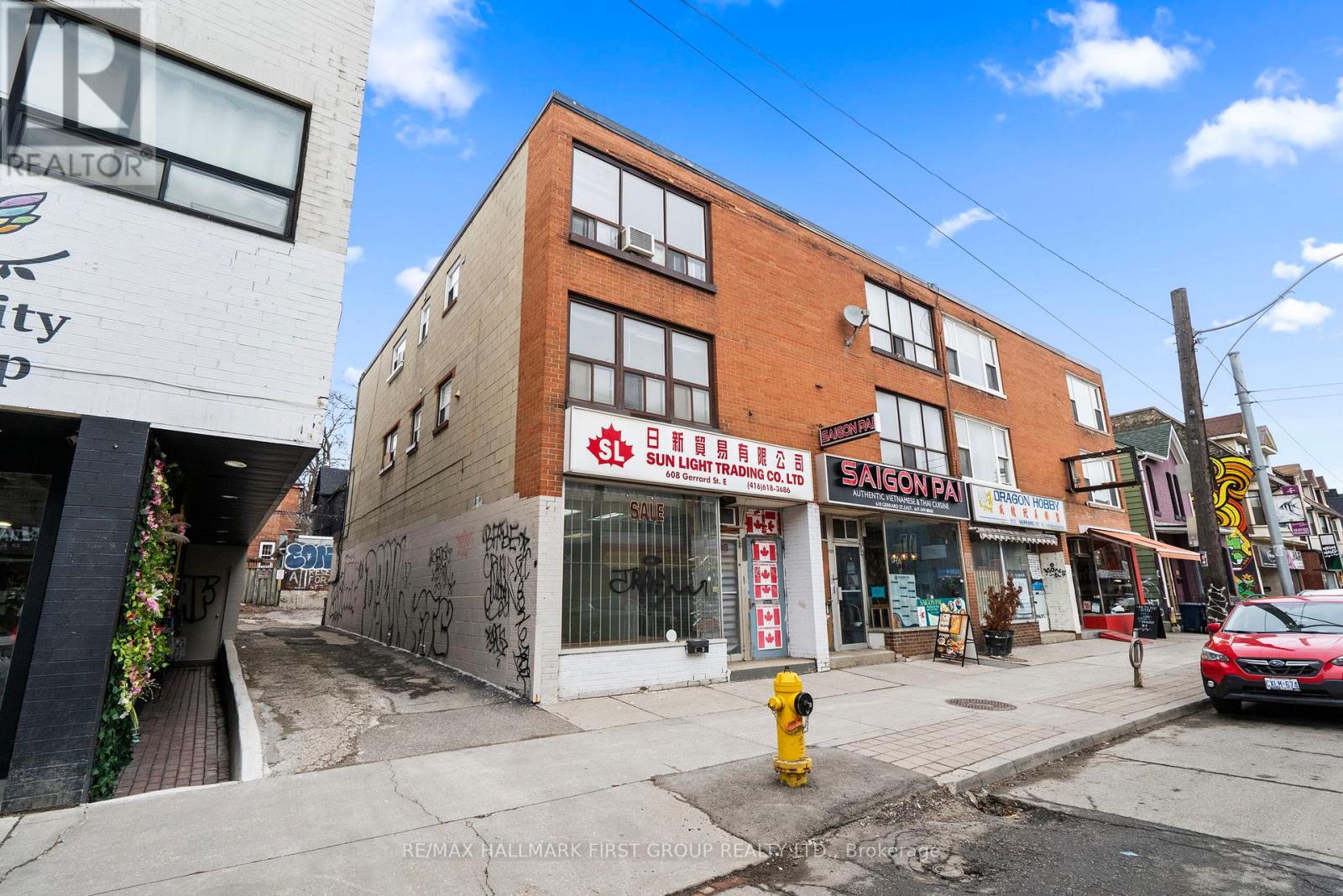 A street view of a building with a red car parked in front.