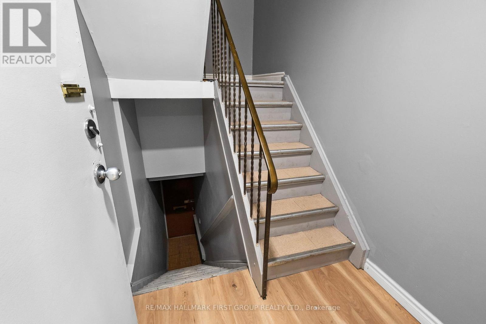 A staircase with a wooden handrail and beige steps leading to a small landing.