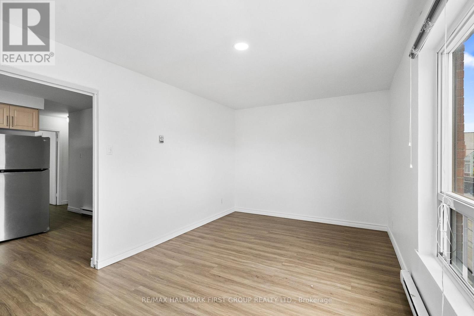 A spacious, empty room with wooden flooring and white walls.