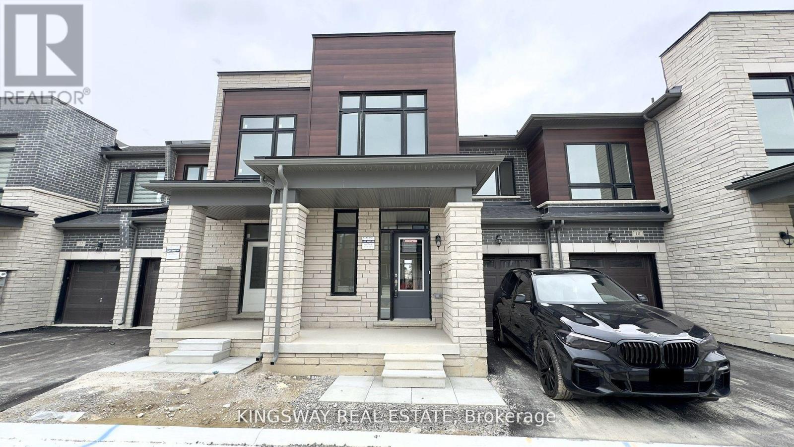 A black BMW is parked in front of a two-story house.