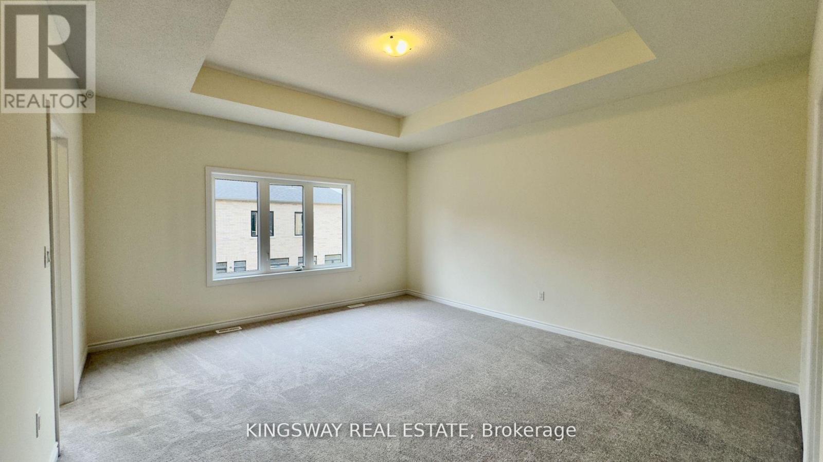 A room with a carpeted floor and a window with a view of a building.