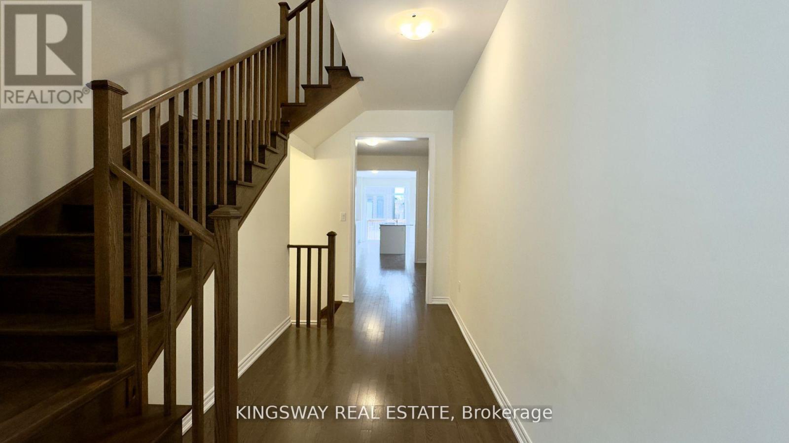 A hallway with a staircase and a door at the end.