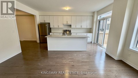 A kitchen with white cabinets and a refrigerator.