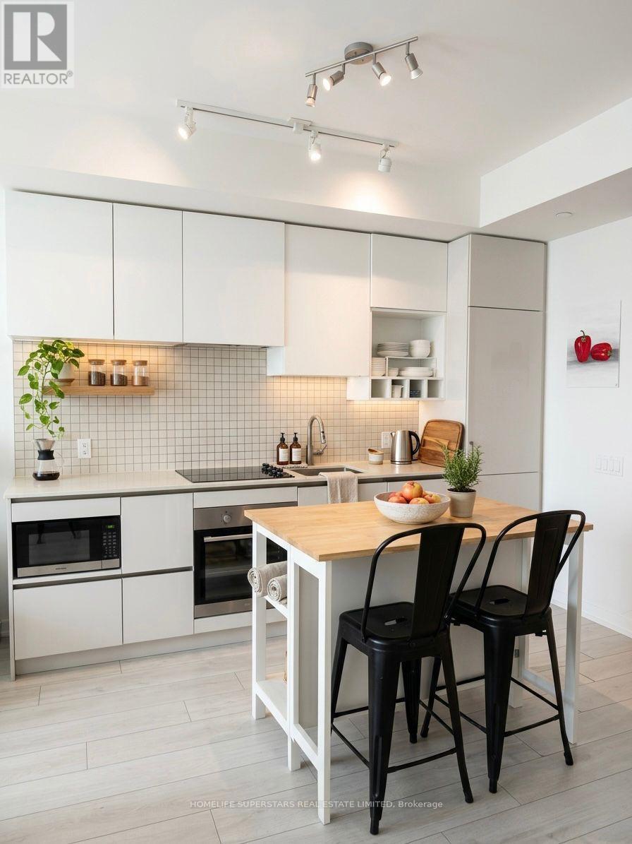 A modern kitchen with white cabinets and black chairs.