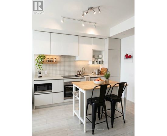 A modern kitchen with white cabinets and black chairs.