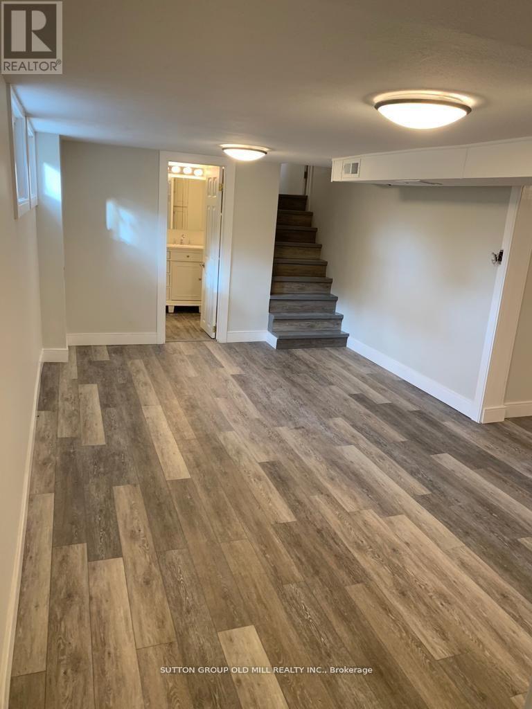 A hallway with wood flooring and a staircase.