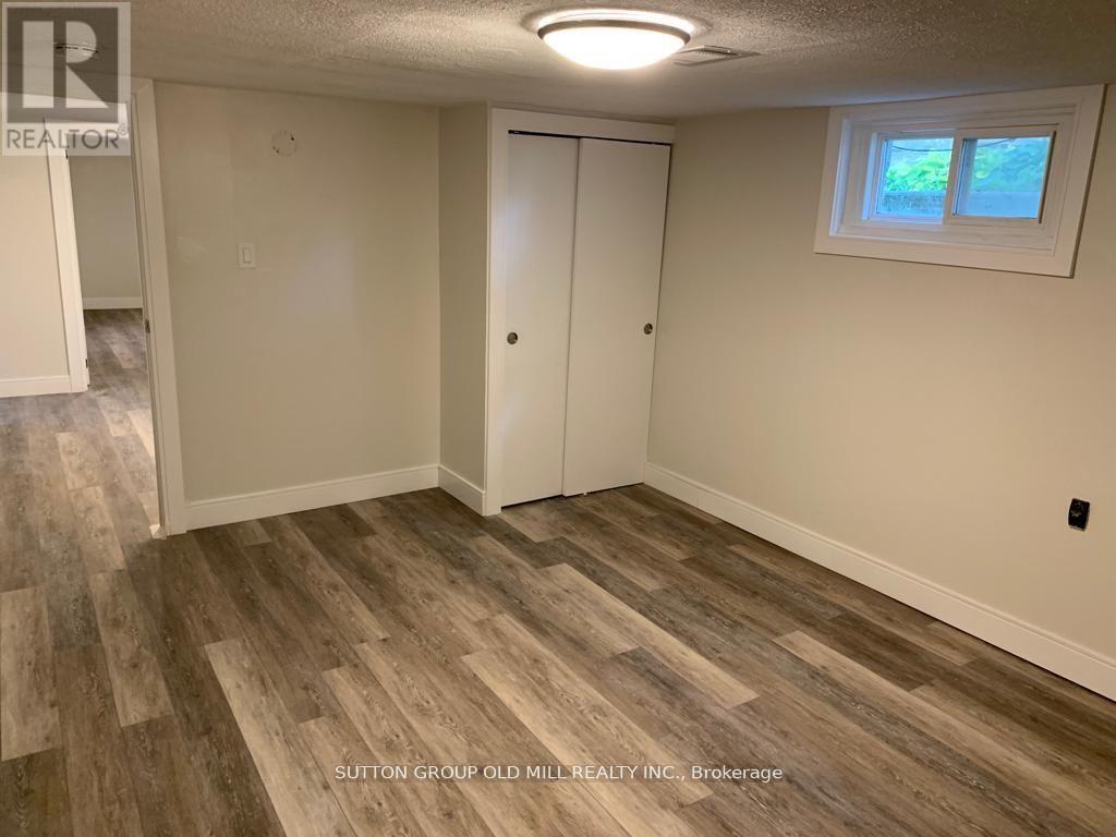 A room with wood flooring and a window with a view of trees.