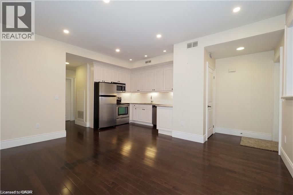 A spacious kitchen with white cabinets and a dark wood floor.