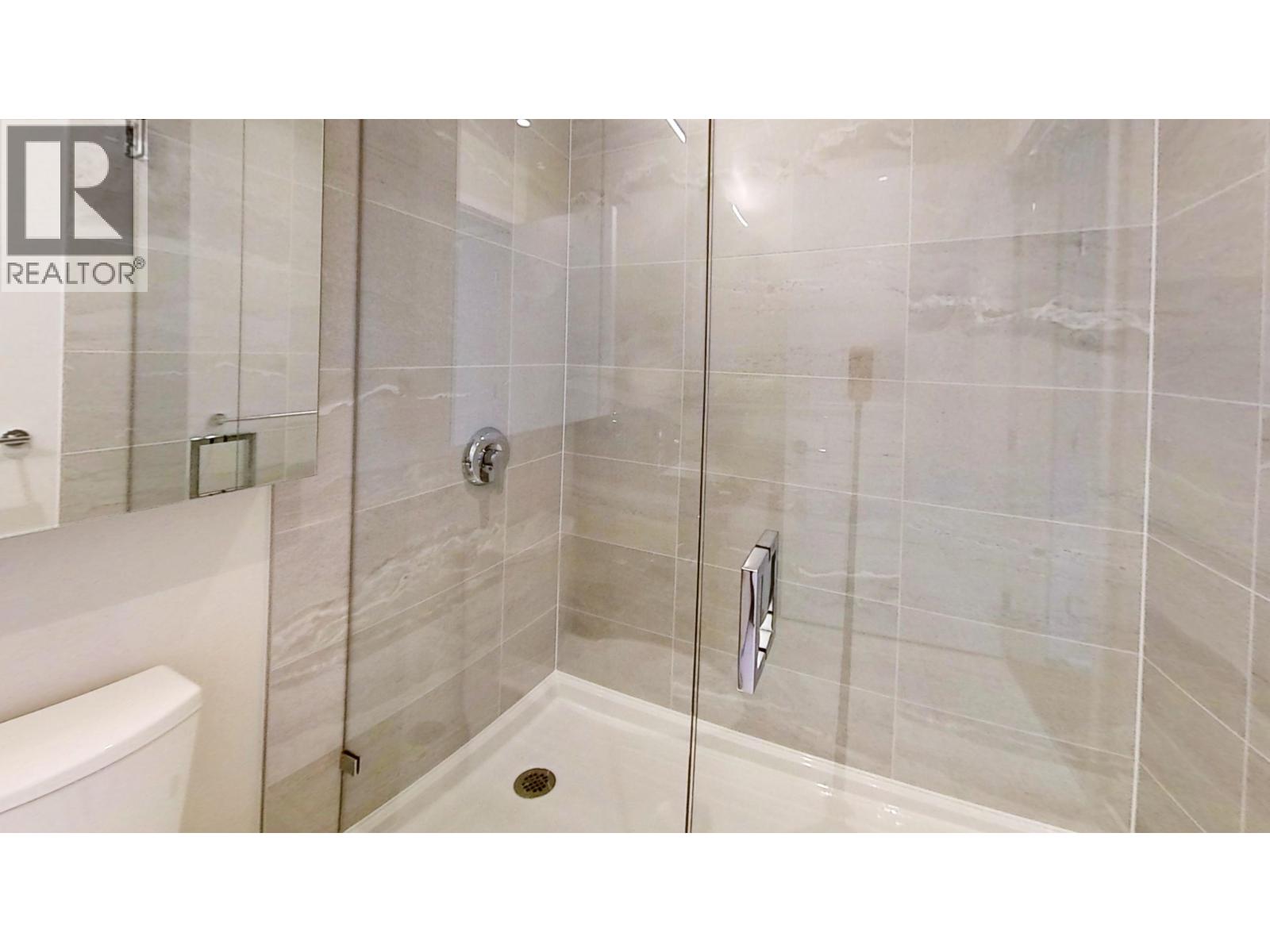 A glass shower stall with a white tub in the corner.