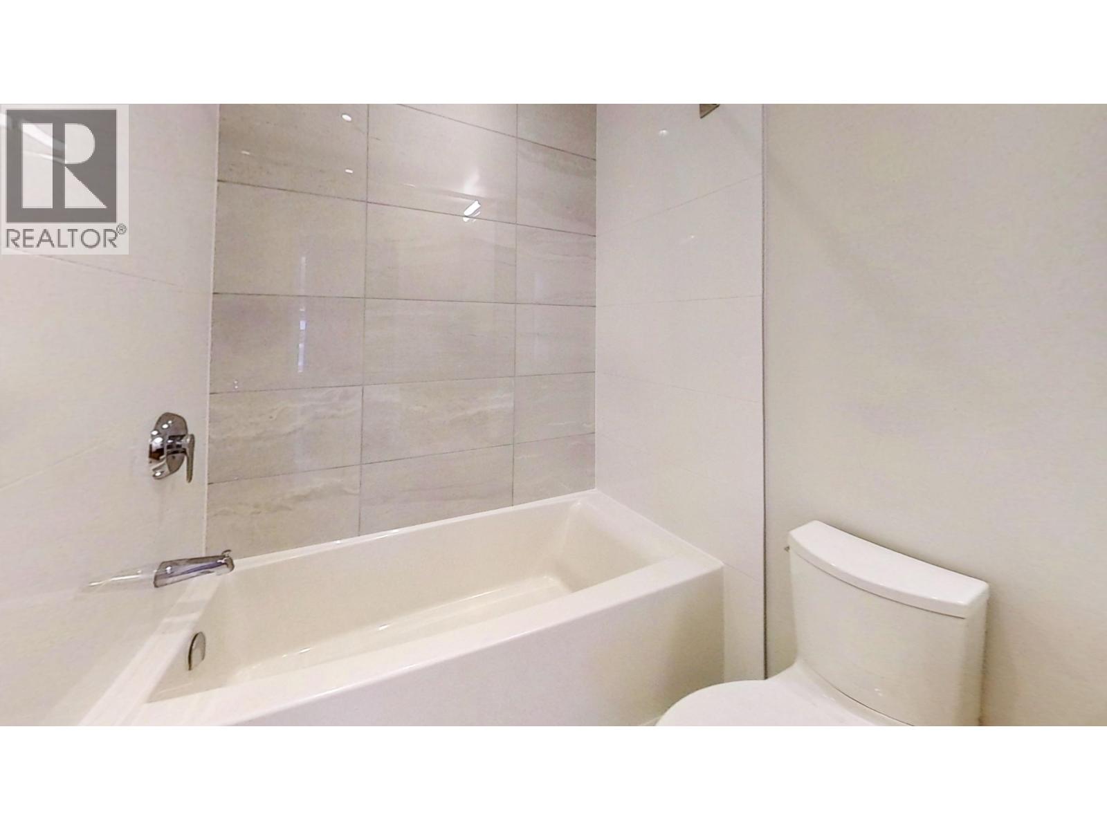 A white bathroom with a tub and toilet.