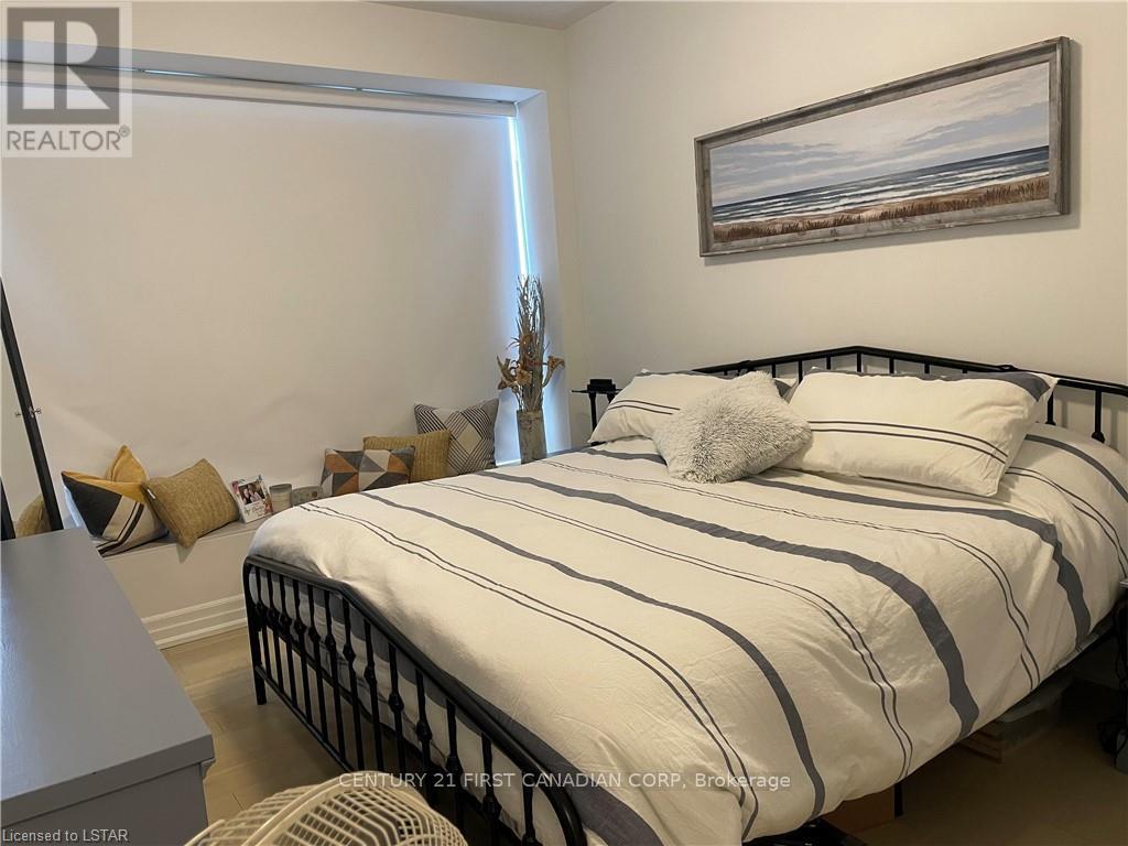 A bedroom with a bed, nightstand, and a painting on the wall.