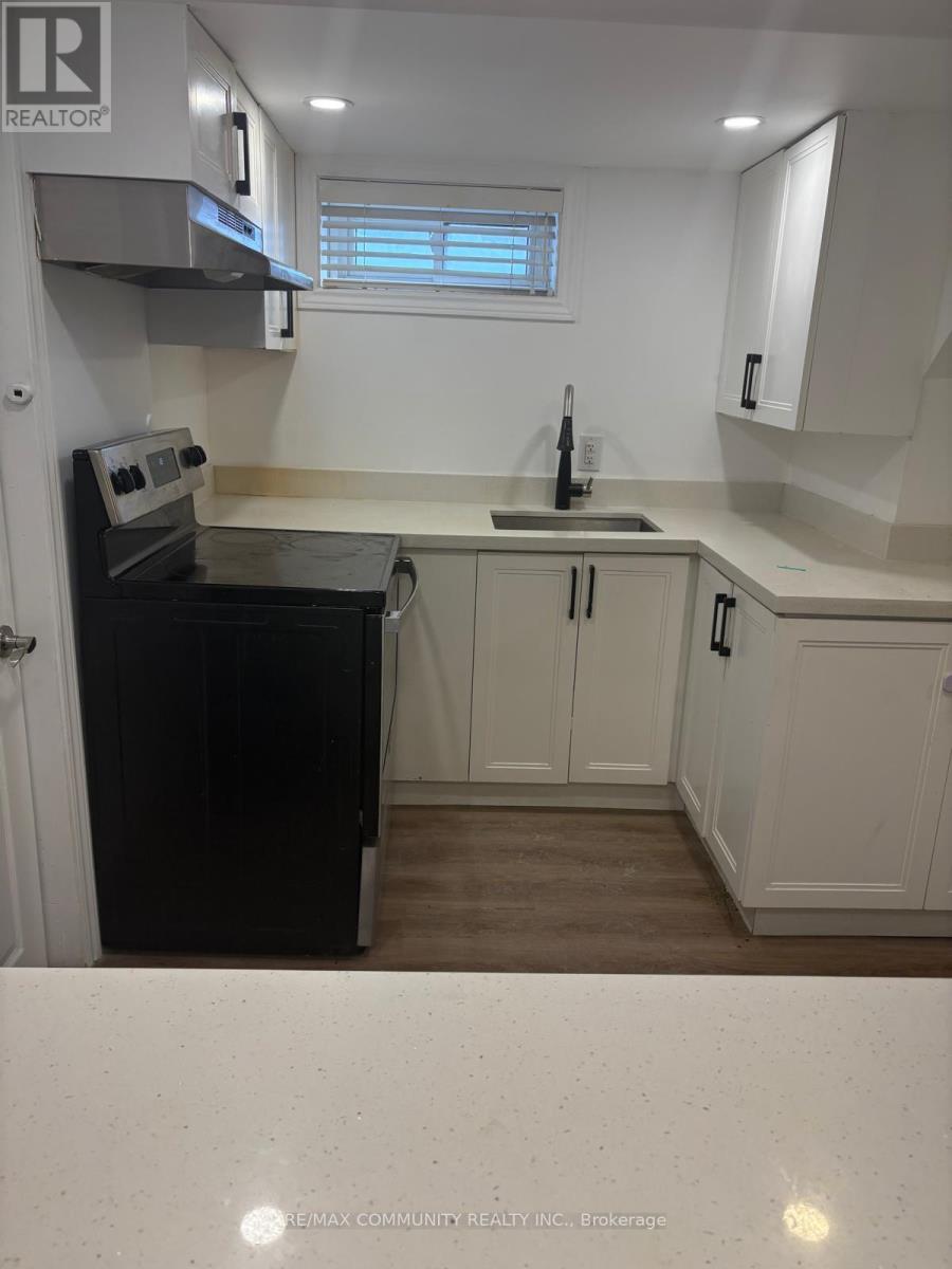 A kitchen with white cabinets and a black fridge.