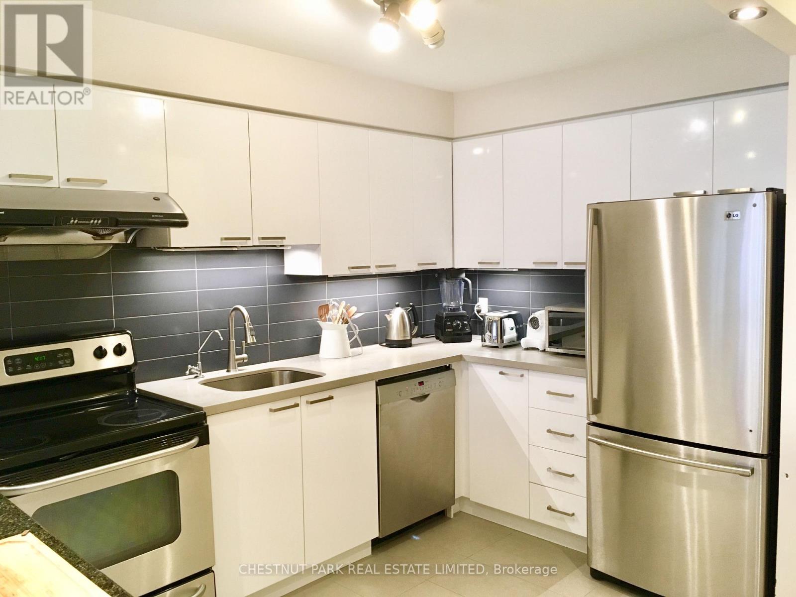 A kitchen with white cabinets and a stainless steel refrigerator.