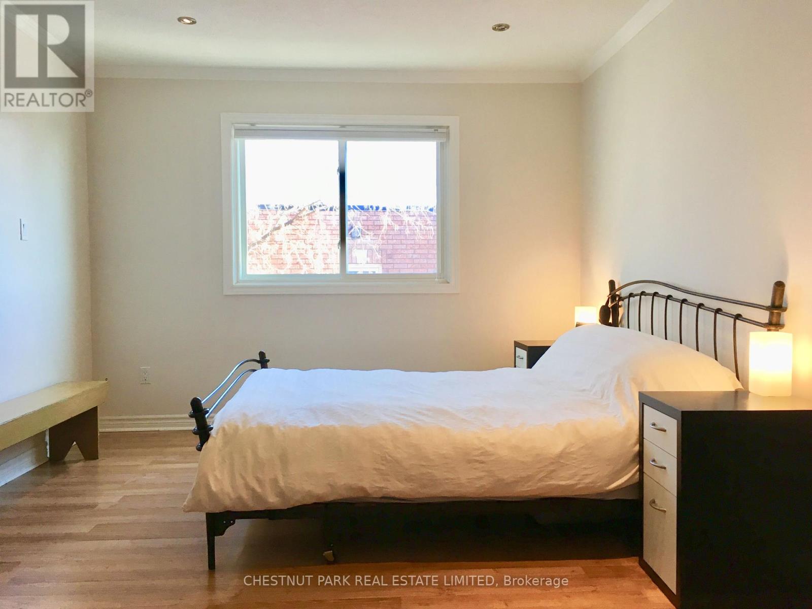 A bedroom with a bed, nightstand, and window.