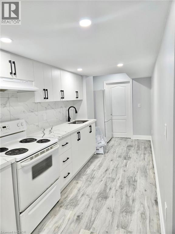 A white kitchen with a stove top oven and a white fridge.