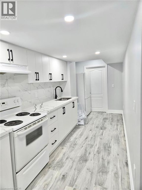 A white kitchen with a stove top oven and a white fridge.