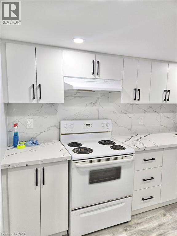 A white kitchen with a stove top oven and white cabinets.