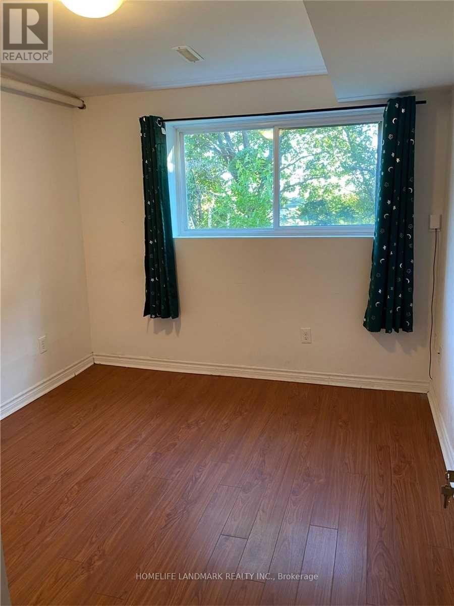 A room with wooden flooring and a window with curtains.