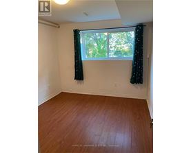 A room with wooden flooring and a window with curtains.