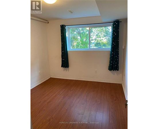 A room with wooden flooring and a window with curtains.