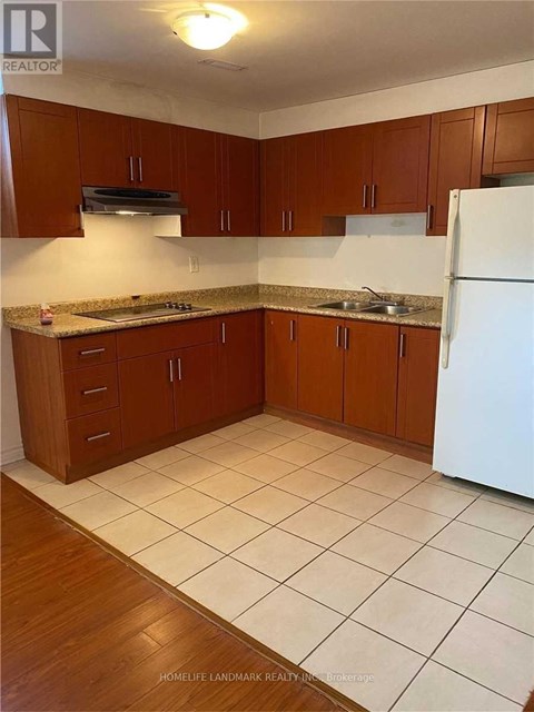 A kitchen with brown cabinets and a white refrigerator.