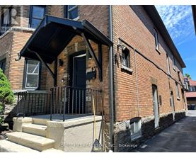 A brick building with a black awning and a black gate.