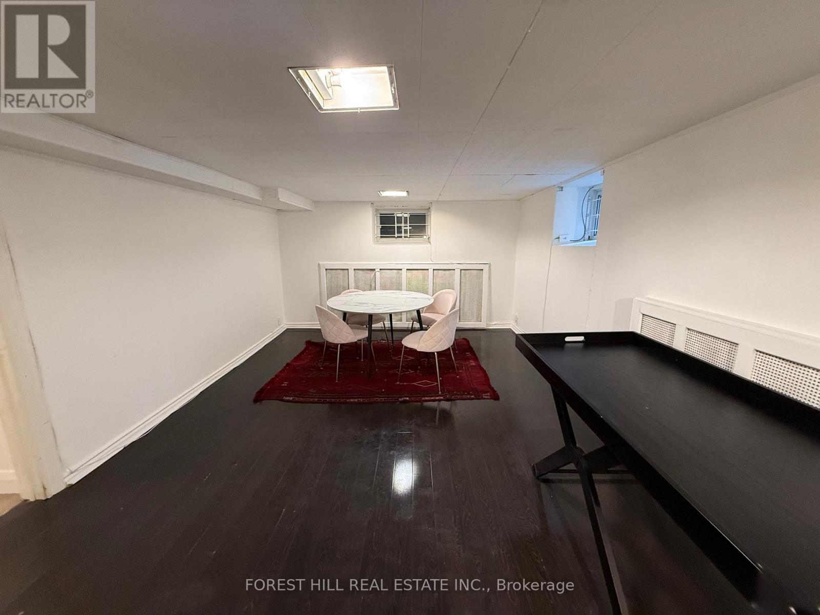 A spacious room with a white couch and a red rug.