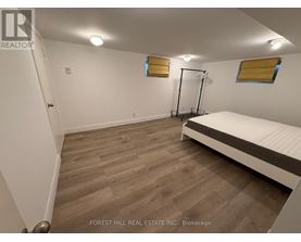 A bedroom with a bed, wooden floor, and a window with yellow blinds.