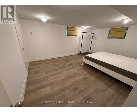 A bedroom with a bed, wooden floor, and a window with yellow blinds.