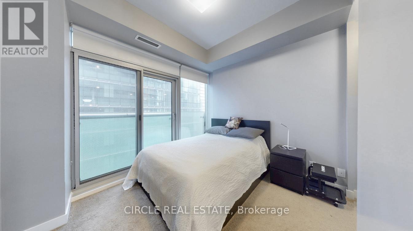 A bedroom with a bed, nightstand, and window.