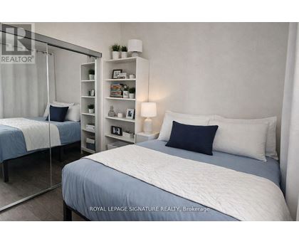 A bedroom with a bed, nightstand, and a shelf with decorative items.