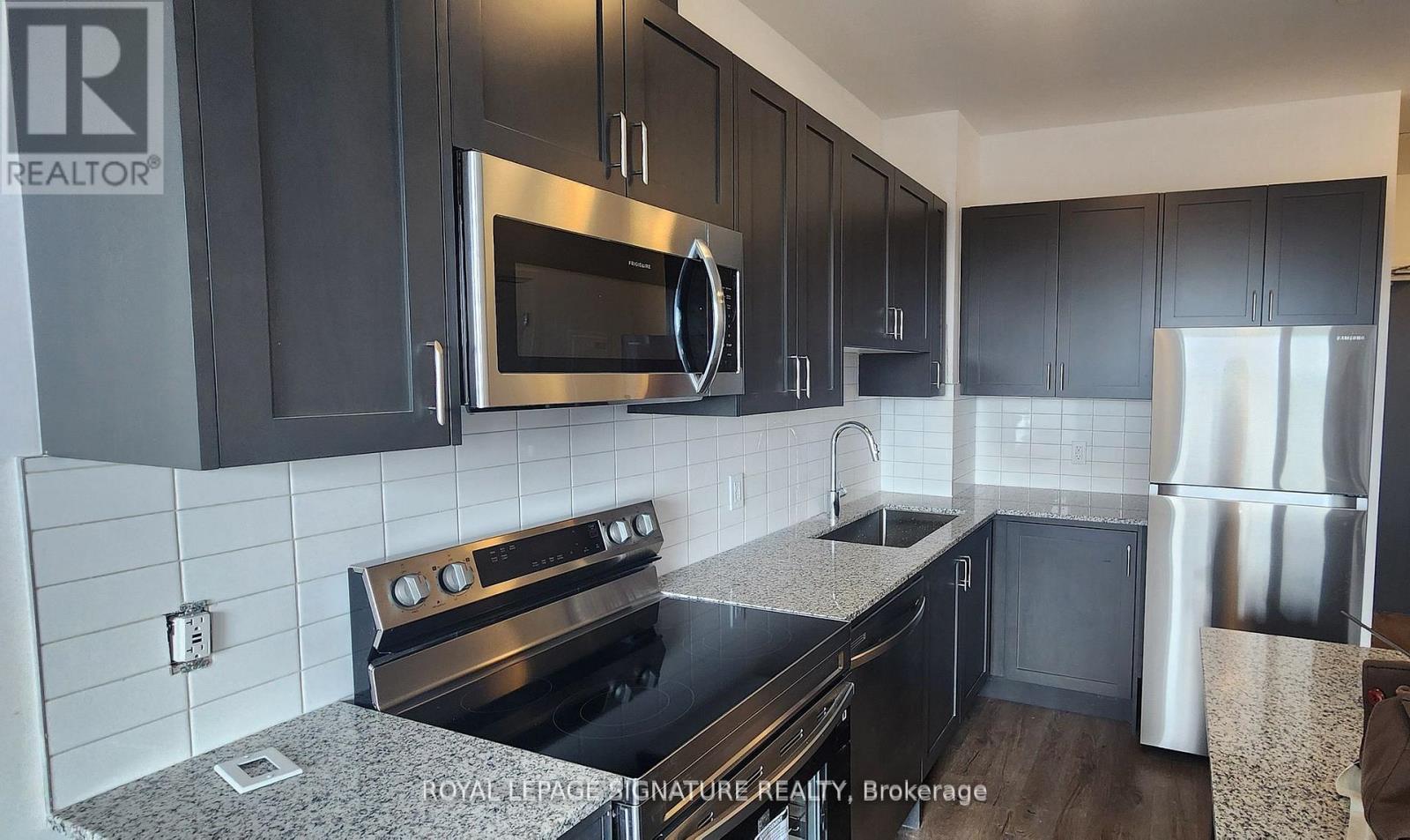 A kitchen with black cabinets and stainless steel appliances.