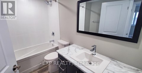 A bathroom with a toilet, sink, and mirror.