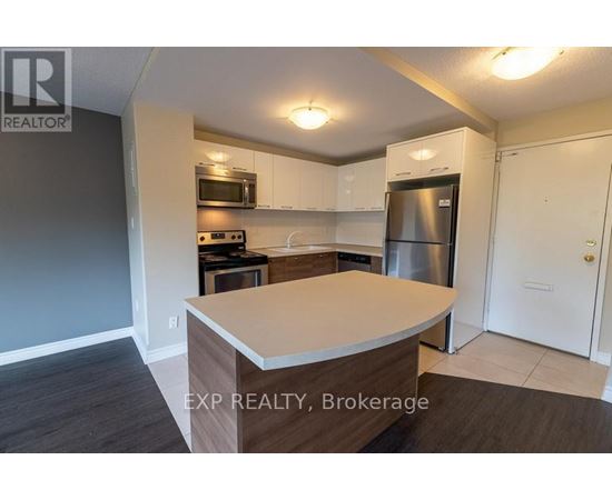 A kitchen with a refrigerator, microwave, and oven.
