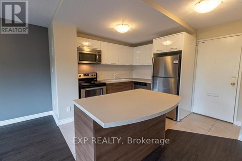 A kitchen with a refrigerator, microwave, and oven.