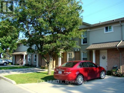 A red car is parked in front of a house.