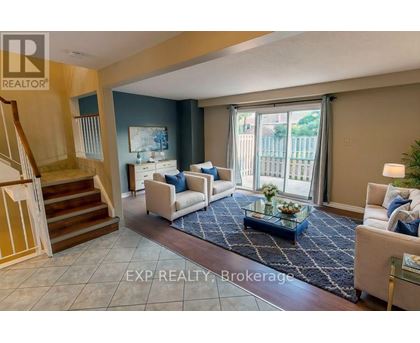 A living room with a staircase and a glass table.