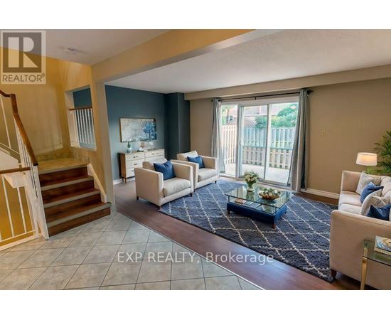 A living room with a staircase and a glass table.