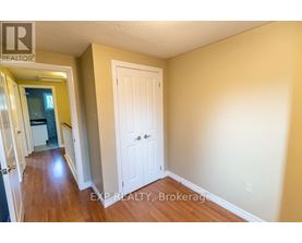 A hallway with a white door and EXP Realty, Brokerage written on the wall.