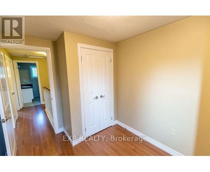 A hallway with a white door and EXP Realty, Brokerage written on the wall.