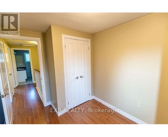 A hallway with a white door and EXP Realty, Brokerage written on the wall.